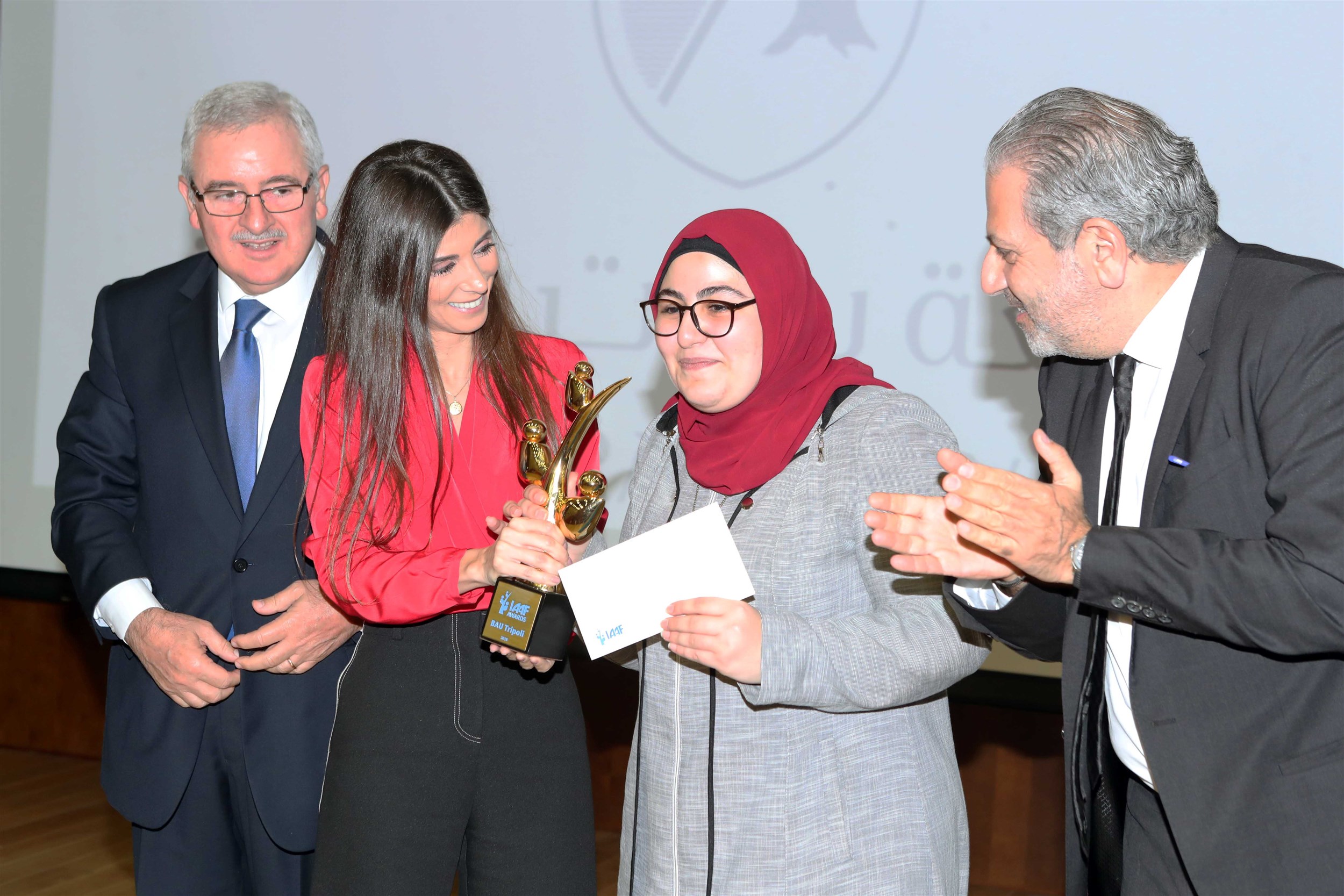 the winning student fatima al- fawal receives her monetary prize of $10,000 and trophy.